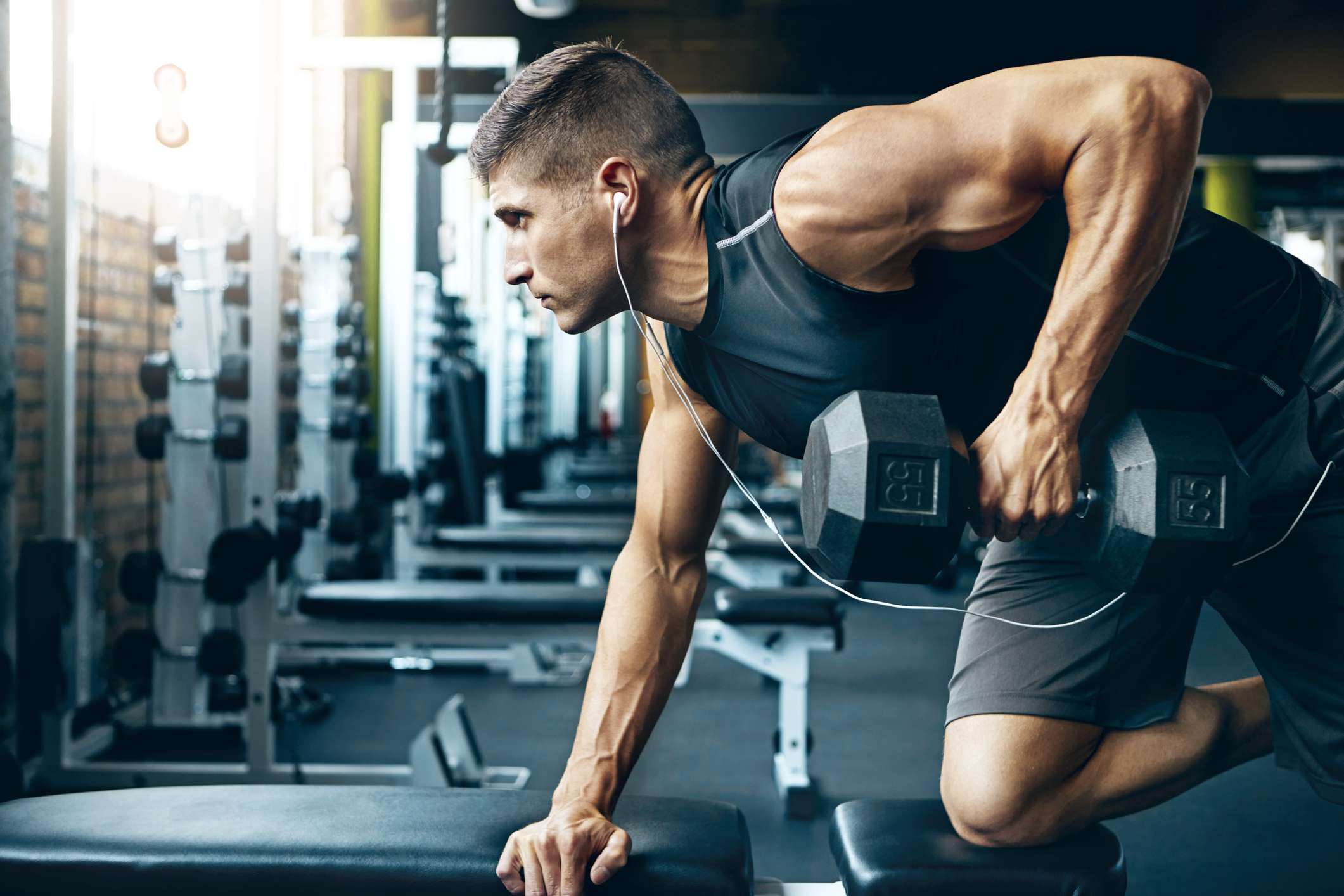 A man doing bent over dumbbell rows, getting in a quick arm day routine workout.